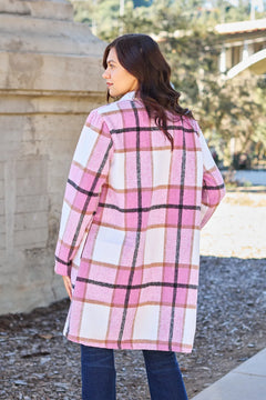 Woman wearing a pink plaid coat standing outdoors with blurred background