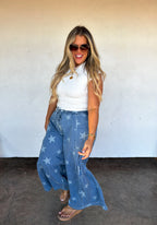 Model wearing Blakeley blue denim palazzo pants with light blue star print and a ruffled bottom hem.