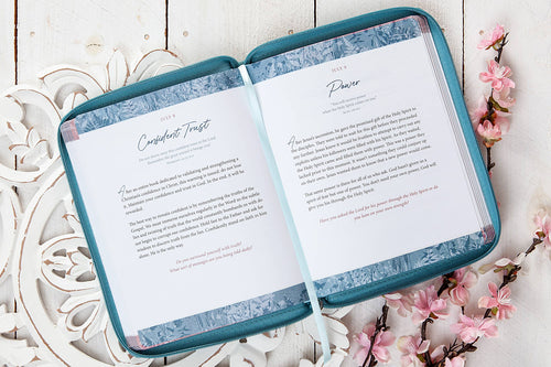 Open book with blue cover on a decorative white surface with floral elements