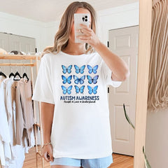 Person wearing a white t-shirt with blue butterfly graphics and 'Autism Awareness' text in a room.