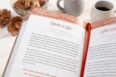 Open book with a red bookmark on a white surface with coffee cups.