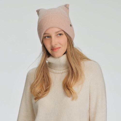 Woman wearing a pink knit hat with cat ears on a light gray background