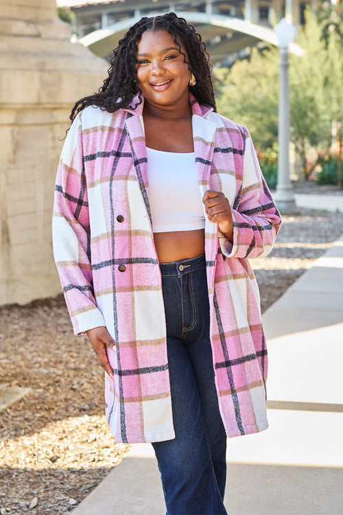 Woman wearing a plaid coat standing outdoors on a sidewalk.