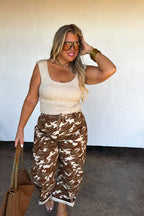 Model walking in Blakeley Desert Brogan camo print barrel jeans with a cream top and brown bag.