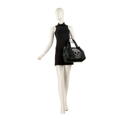 Mannequin wearing a black dress holding a black handbag with skull design on a white background