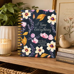 Floral notebook titled 'A Time For Everything' on a shelf with books and a candle.