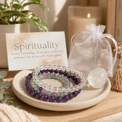 Set of beaded bracelets on a ceramic dish with a card labeled 'Spirituality' and a crystal ball in the background.