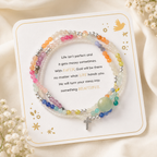 Messy Life Charm Bracelet displayed on its sentiment card with multicolor beads, silver accents, and a small cross charm on a soft ivory background with delicate flowers.
