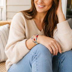 Woman wearing the colorful Messy Life Charm Bracelet with a cream sweater and jeans in a relaxed cozy lifestyle setting.