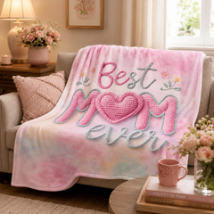 Pink Best Mom Ever fleece throw blanket draped over a cozy couch with floral accents, a pink mug, and soft home décor styling.