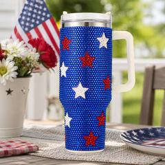 Travel mug with star pattern on a table with American flag and flowers in the background