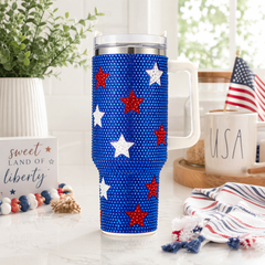Blue tumbler with red and white stars on a table with American flag and 'USA' mug.