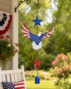 Patriotic eagle hanging chime displayed on a porch with red white and blue bunting, flowers, and an American flag pillow.