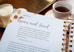 Open planner with a quote on a table with a cup of coffee and a glass of milk.