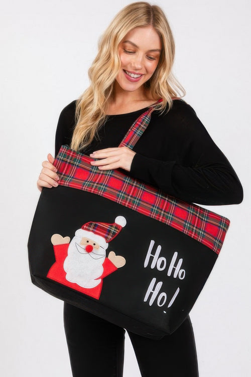 Woman holding a black tote bag with Santa Claus design and 'Ho Ho Ho!' text on a white background