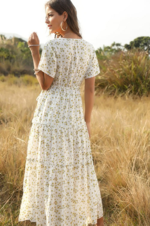 Woman in a white floral dress standing in a grassy field