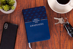 Blue book titled 'Bible Promises for Graduates' on a wooden surface with a phone, keys, and coffee cup.