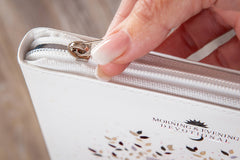 Hand opening a white book titled 'Morning & Evening Devotional' with a blurred background.