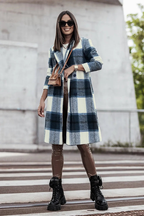 Woman wearing a plaid coat and brown boots on a city street.