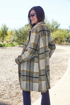 Woman wearing a plaid coat outdoors with trees in the background