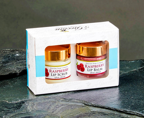Set of raspberry lip scrub and balm in a branded box on a dark surface.