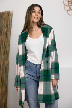 Woman wearing a green and white plaid coat with a plain background