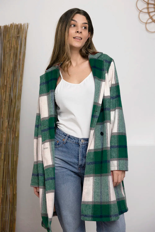Woman wearing a green and white plaid coat with a plain background