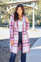 Woman wearing a pink plaid coat outdoors on a sunny day.