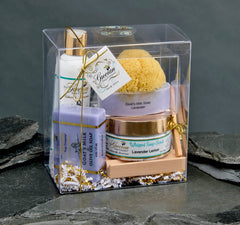 Set of skincare products in a clear gift box on a stone surface with a dark background