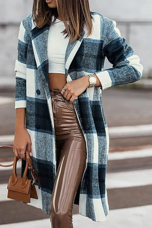 Woman wearing a plaid coat with a white top and brown pants, holding a brown handbag.