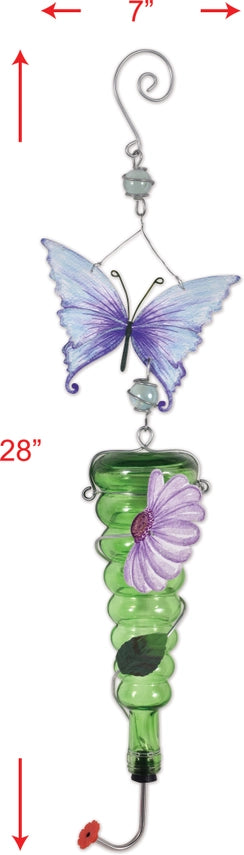 A hanging 28-inch green glass hummingbird feeder with a decorative metal purple butterfly and flower accent in a garden setting.
