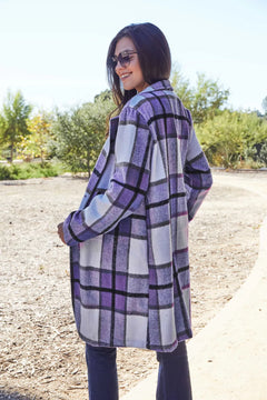 Woman wearing a purple and white checkered coat outdoors on a sunny day.