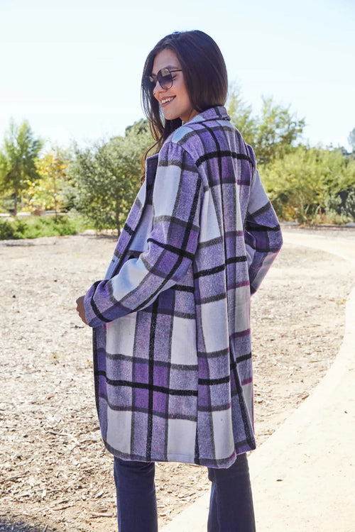 Woman wearing a purple and white checkered coat outdoors on a sunny day.