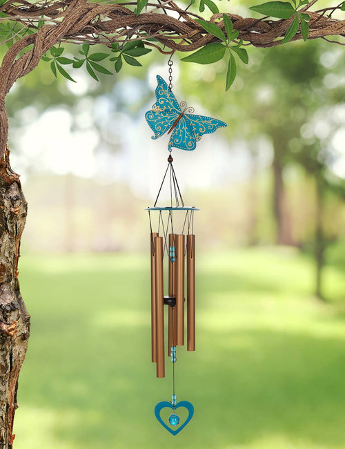 Butterfly-shaped wind chime hanging from a tree with a blurred garden background