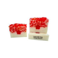 Two bars of goat's milk soap with red and white marbled pattern on a white background.
