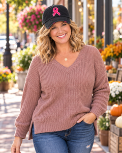 Mature woman wearing black distressed pink ribbon breast cancer awareness cap with cardigan and flowers