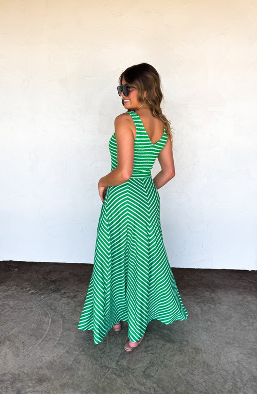 Woman wearing a green and white striped dress against a plain background