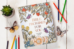 Coloring book titled 'Bible Promises for You' with butterflies and pencils on a wooden surface