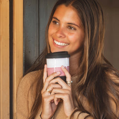 Woman holding a pink and white coffee cup with a wooden door in the background