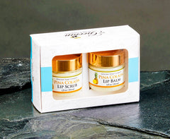 Two lip balm jars in a decorative box on a dark surface