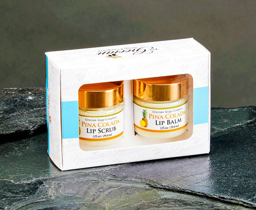 Two lip balm jars in a decorative box on a dark surface