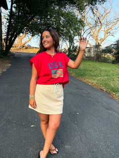 Model wearing a khaki/cream mini jogger skirt with side pockets, paired with a red graphic tee.