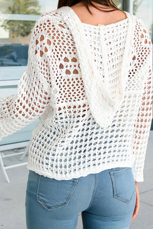 Back view of a white hollow-out crochet knit hoodie styled with jeans, showing the relaxed hood and open knit texture.