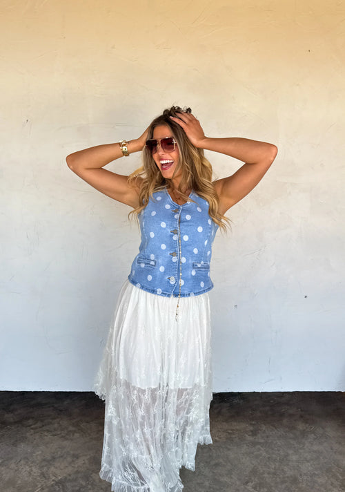 Model wearing the Sprinkle Me Denim Vest with a white lace skirt for a playful summer boutique outfit.