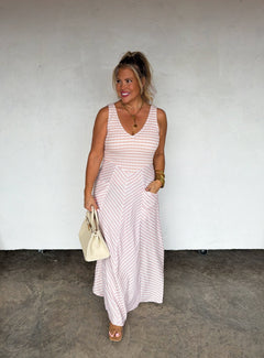 Woman wearing a pink and white striped dress against a plain background