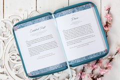 Open book with blue cover on a decorative white surface with floral elements