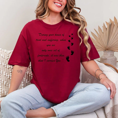 Person wearing a red t-shirt with a motivational quote and footprints, sitting on a couch.