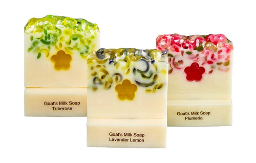 Three bars of goat's milk soap with floral designs on a white background