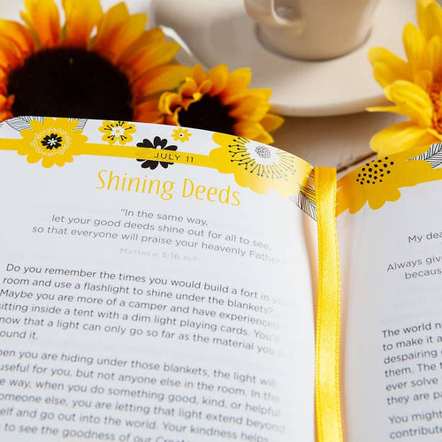 Open book with yellow floral design on a table with sunflowers