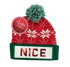 Red holiday pom hat with green brim and sequins reading “NICE.”